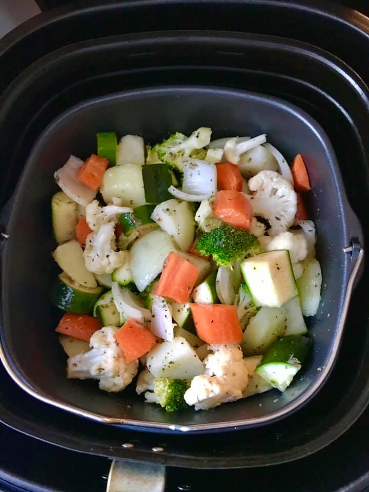 Vegetables stacked in an air fryer ready for cooking